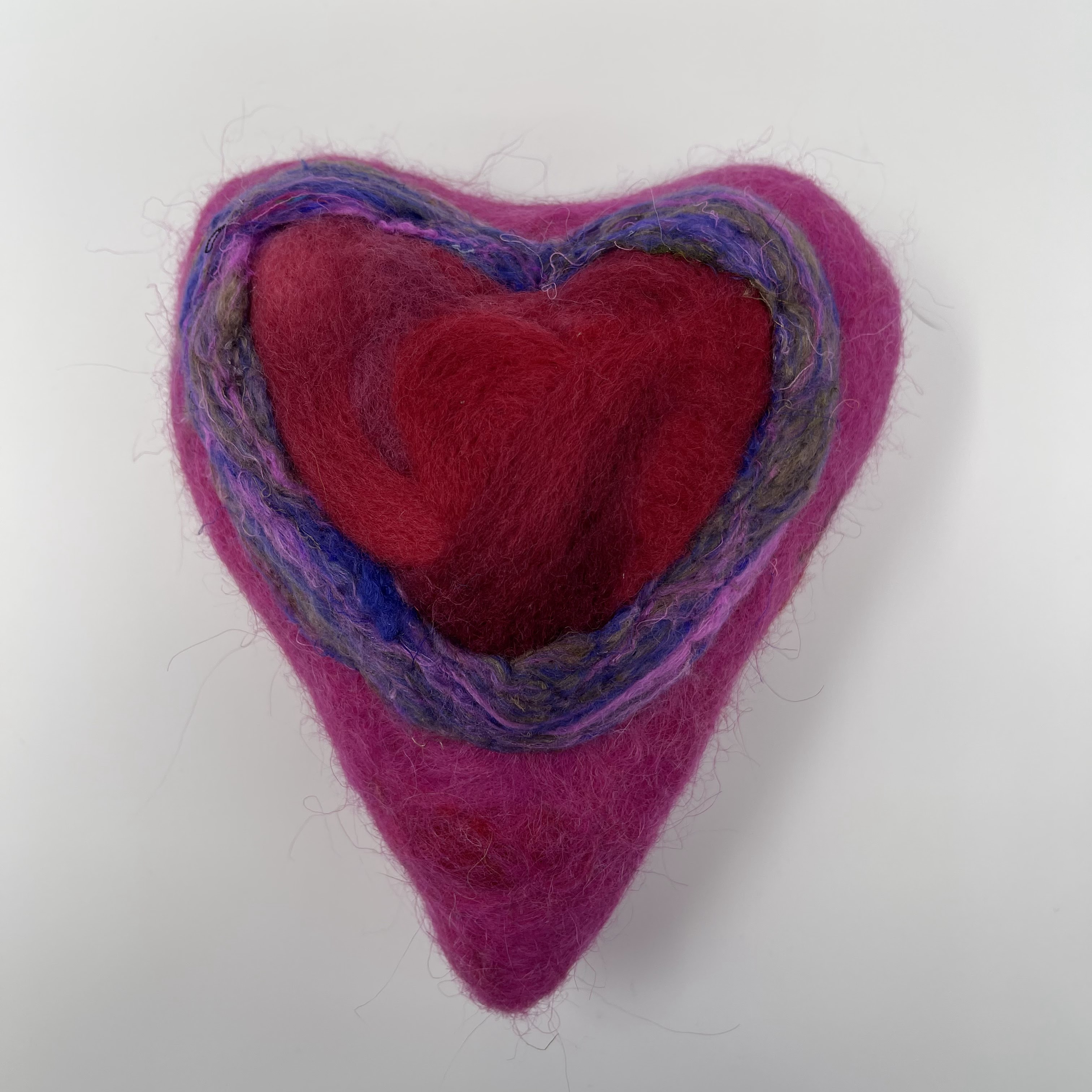 #13 Stuffed magenta felted heart with red heart center and multicolor trim. Hung on gold chord. 7.5x6x3"