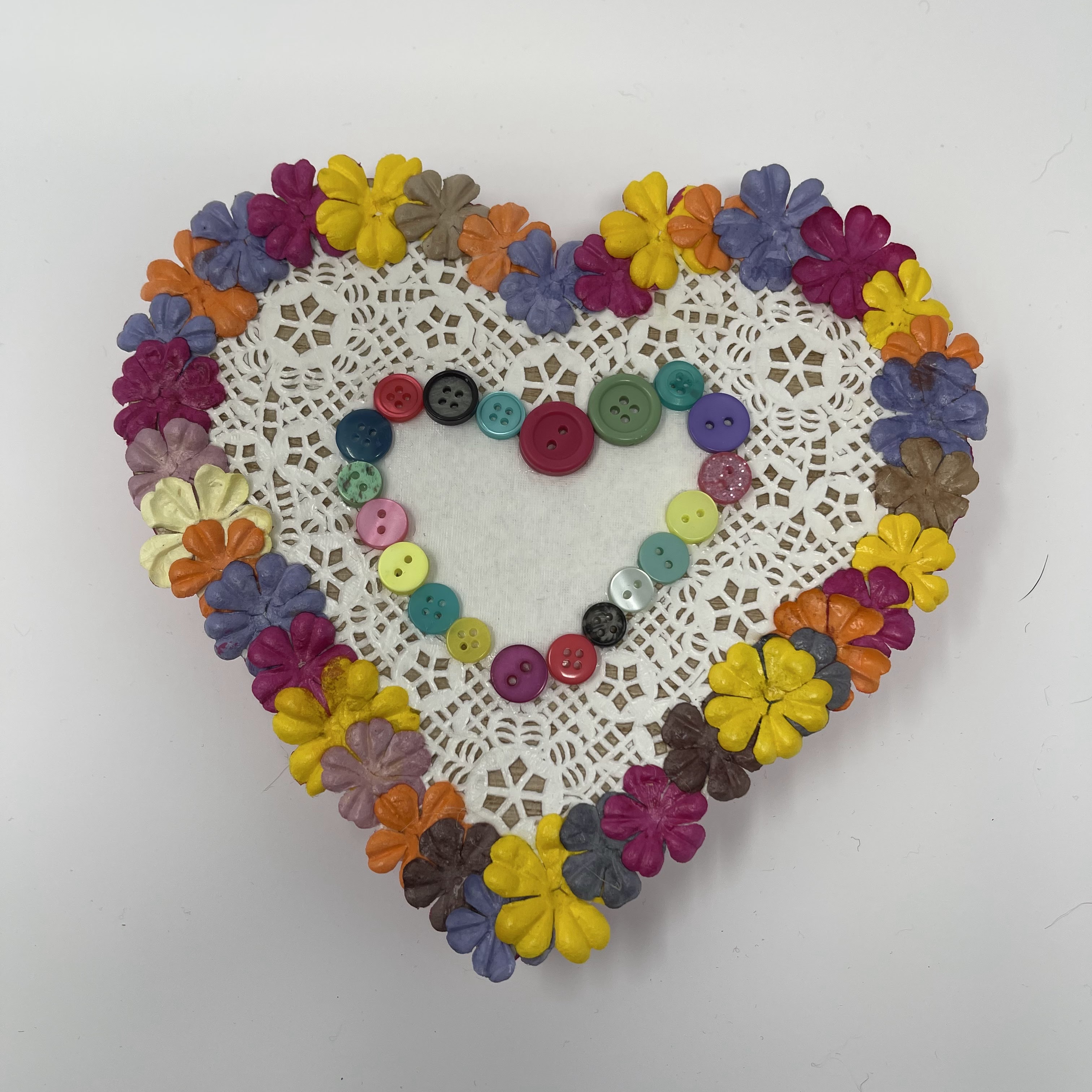 #24 Wood heart decorated with paper doilies and rainbow flowers and buttons.7x7x1"