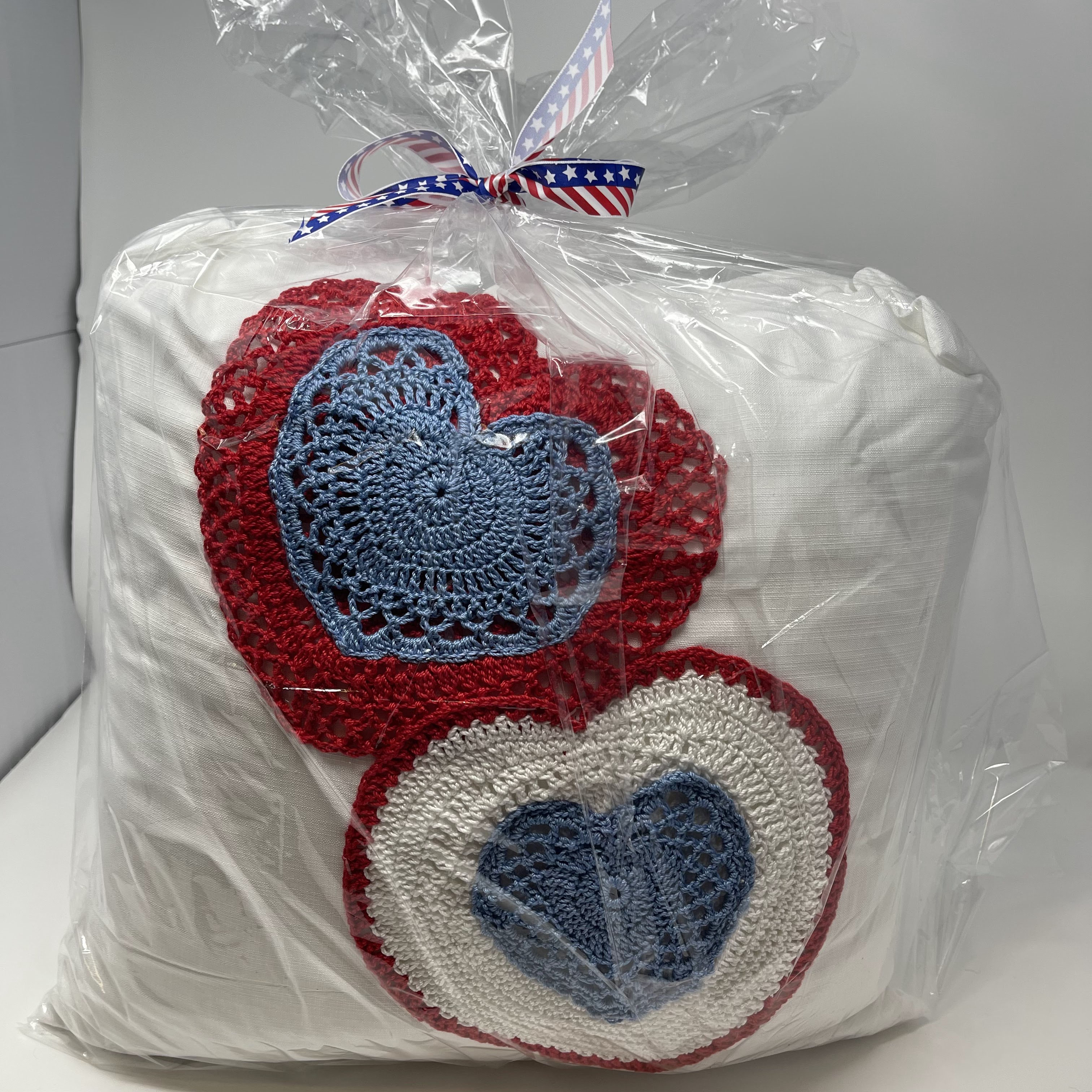 #26 White pillow with heart shaped, crocheted doilies in red, white, and blue.15x15x8"