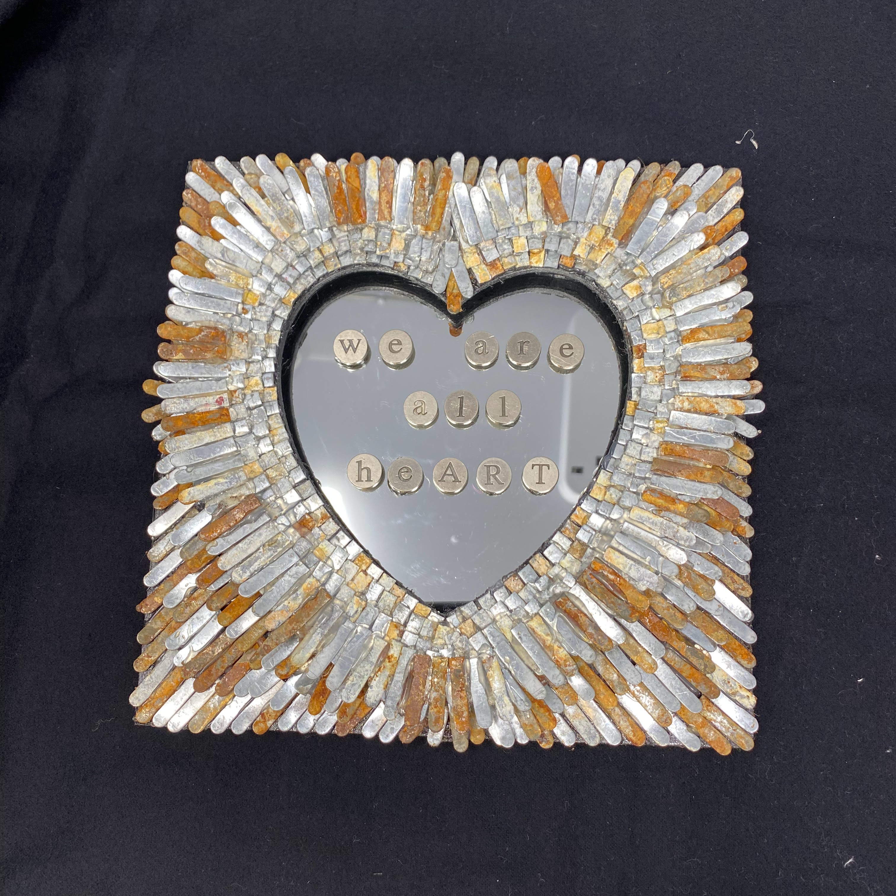 #38 Metal feather-like mosaic with heart shaped mirror with typewriter font message we are all heart