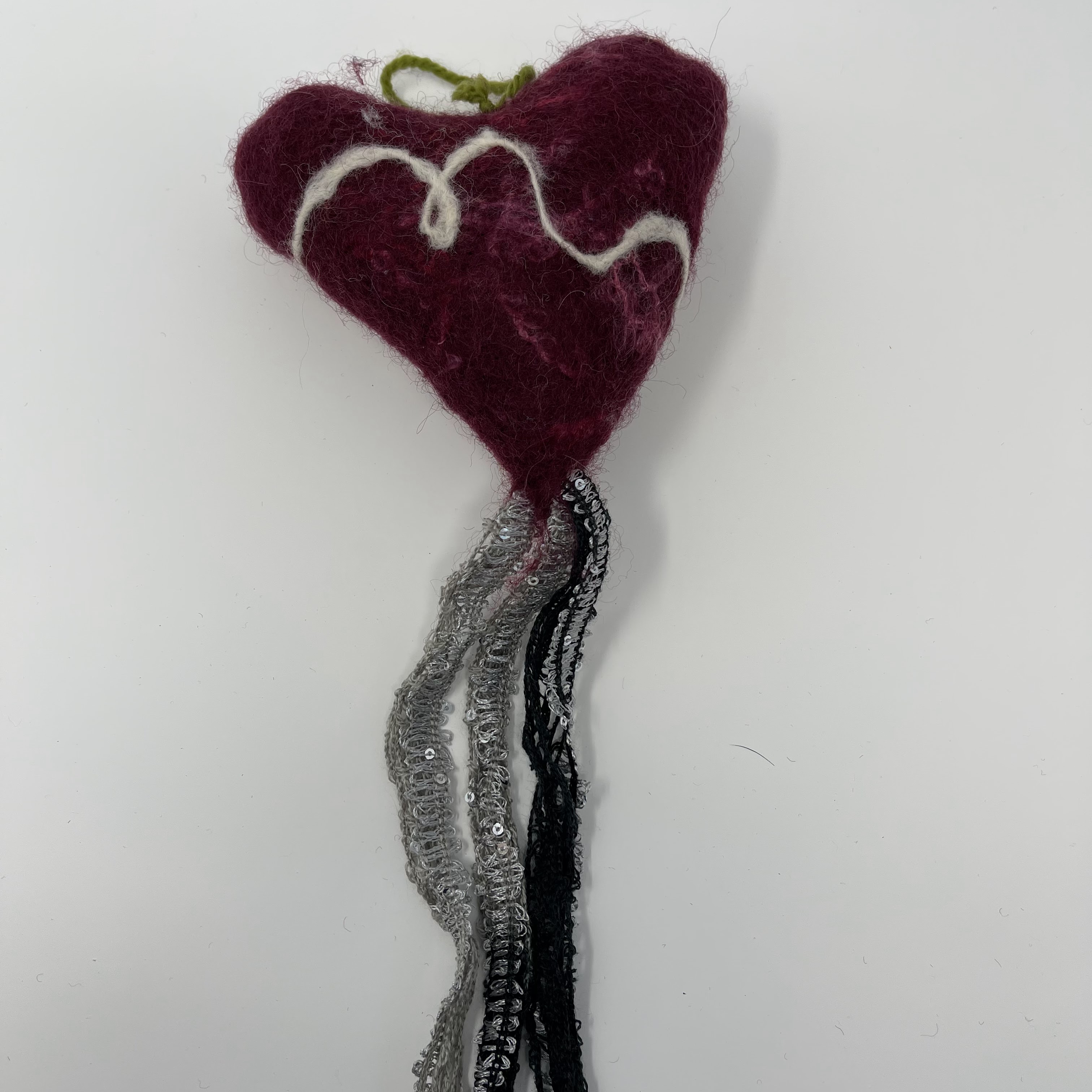 #41 Stuffed felted burgundy heart with white squiggle decorations and textured black and silver sparkled tassle. 14x6x2"