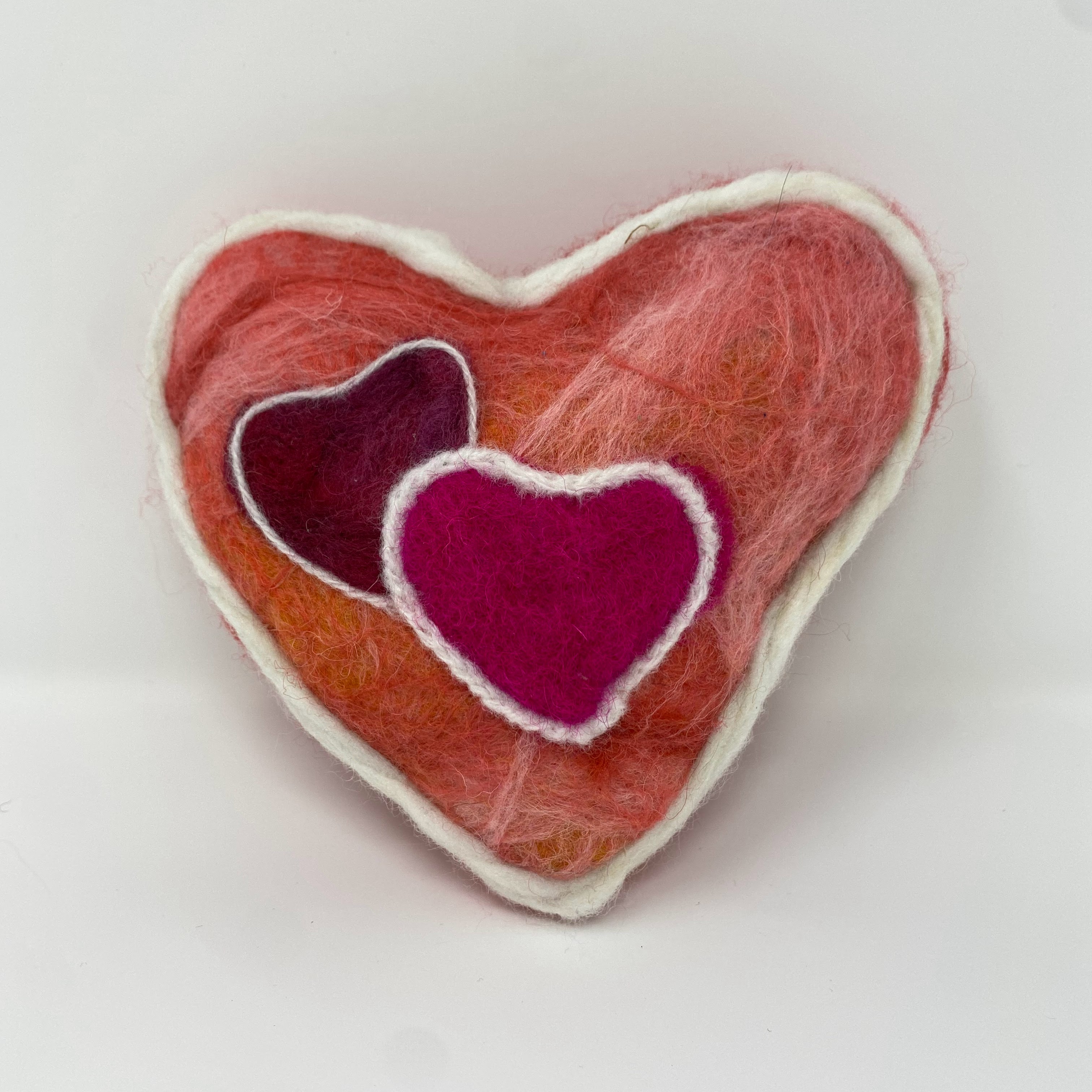 #54 Stuffed felted coral heart with two overlapping maroon and pink felted hearts with white outline design